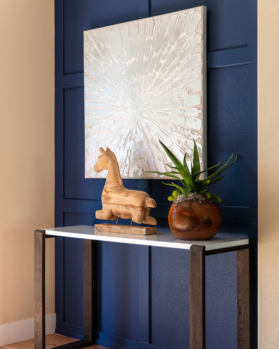 console table with wooden giraffe figurine and hanging picture on blue painted wall