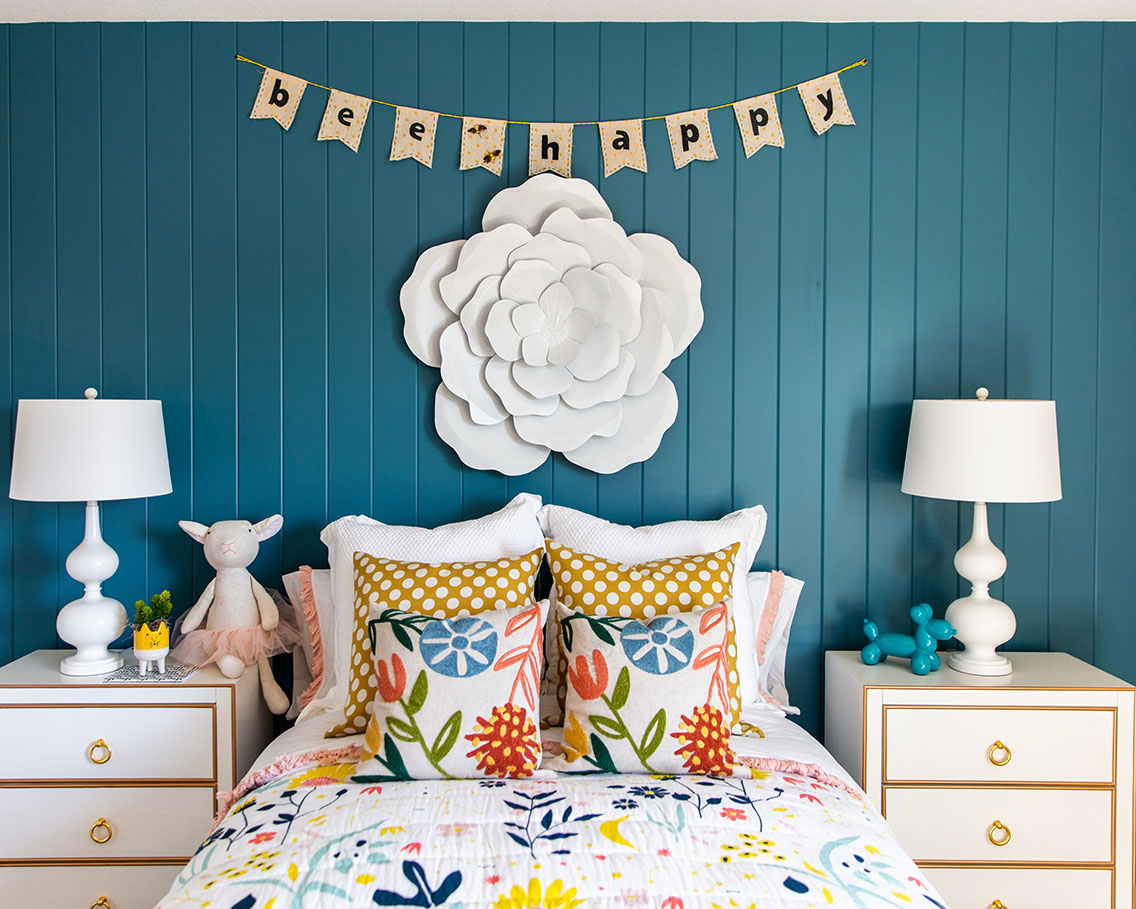 children's bedroom with floral bedding, blue painted walls and decorative flower on wall