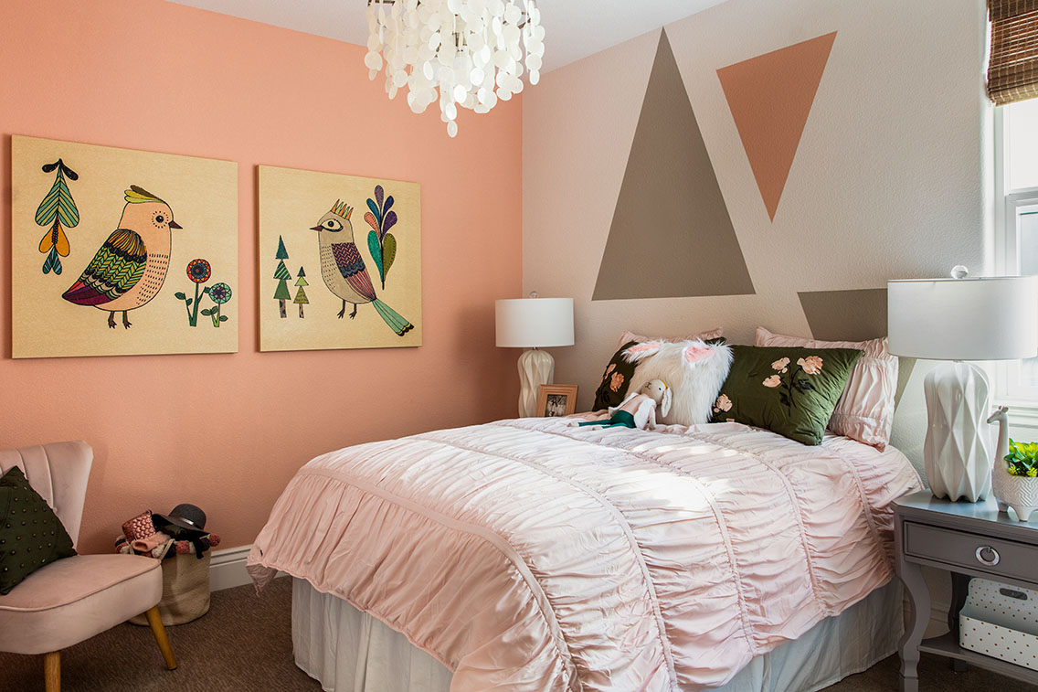 girls bedroom with pink walls, light pink bedding and decorative pictures on wall