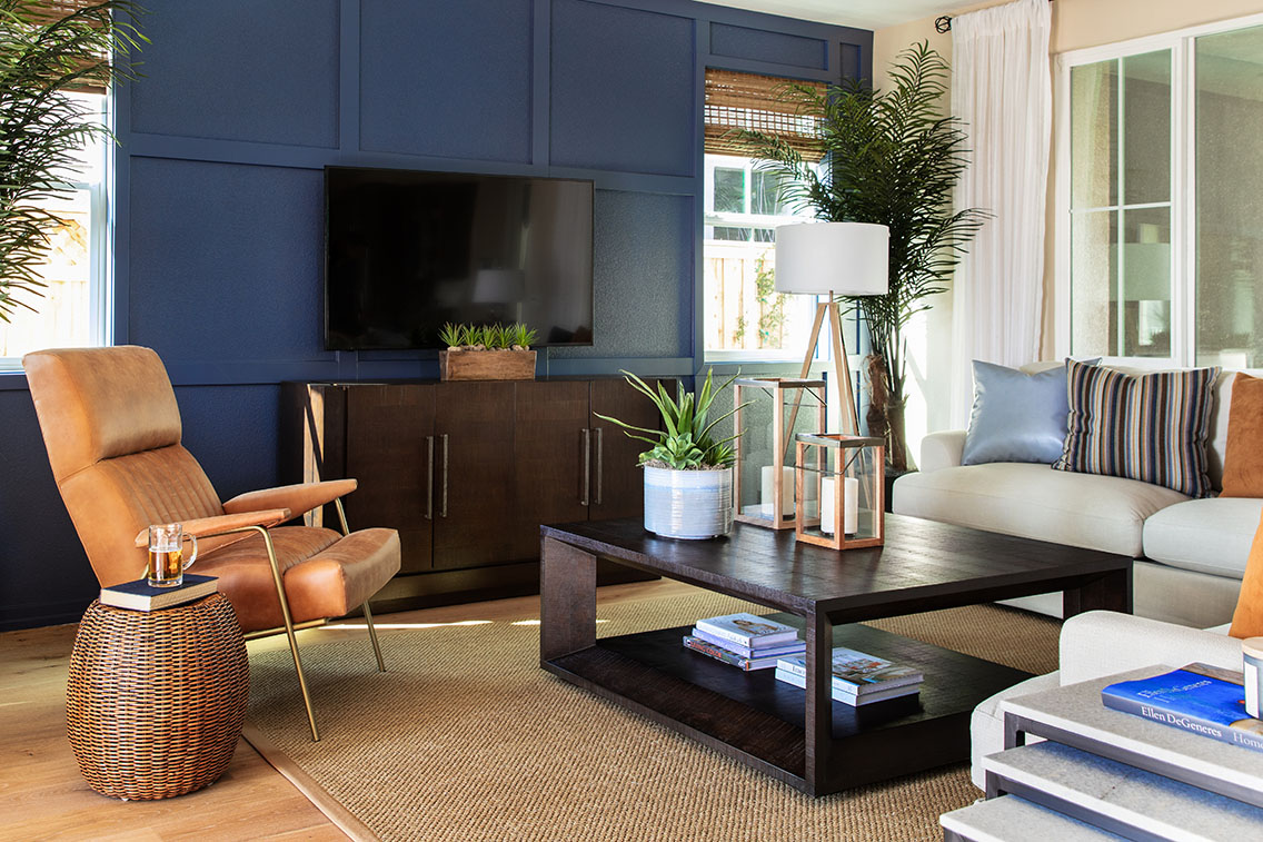 living room furniture set with tan suede chair, white chair with blue and orange pillows and blue painted accent wall