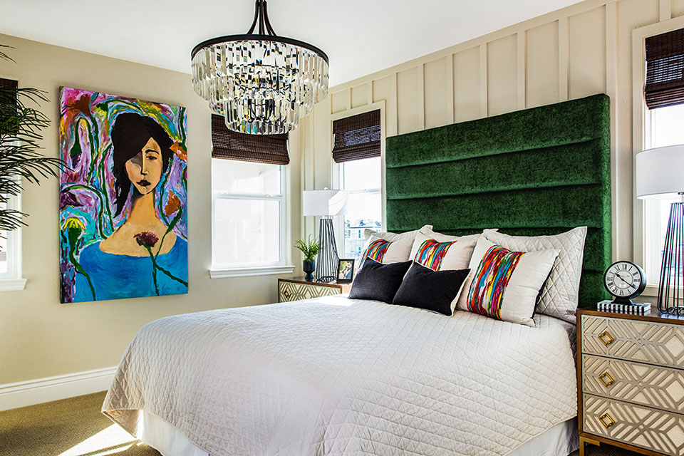 bedroom with large bed, white linen, green headboard, crystal chandelier, and large painting on wall